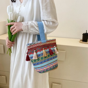 Dettaglio della borsa a secchiello tessuta con motivi geometrici colorati e nappe