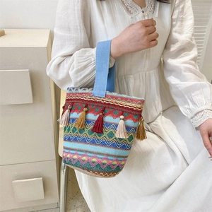 Dettaglio borsa a secchiello bohémien tessuta a mano con frange colorate e motivi a onde