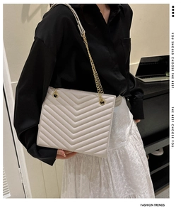 Detail of beige V-quilted chain bag worn by model featuring elegant gold strap