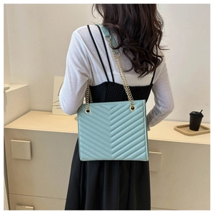 Detail view of mint green V-quilted shoulder bag with gold chain strap on model