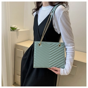 Detail of mint green quilted leather shoulder bag with elegant gold chain strap