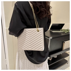 Detail of light beige quilted shoulder bag with chic gold chain strap and V-pattern finish