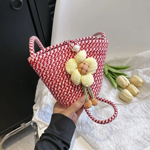 Close-up of red and white woven bucket bag with yellow flower and pearl clasp detail