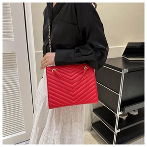 Detail of red V-quilted tote bag featuring gold chain strap and elegant leather handle