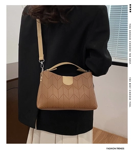 Close-up of brown quilted handbag with beige handles on a model in a stylish setting