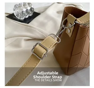Detail of adjustable khaki shoulder strap with silver hardware on brown quilted bag