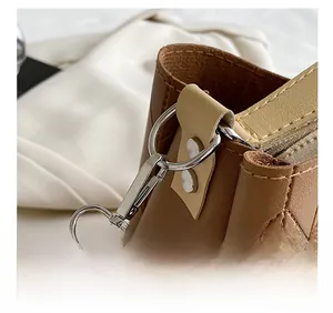 Close-up of silver metal hook and cross-pattern leather detail on brown tote bag