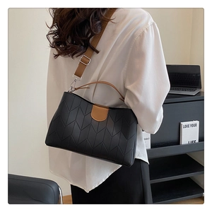 Detail of chic black quilted tote bag with brown straps worn on shoulder by a model