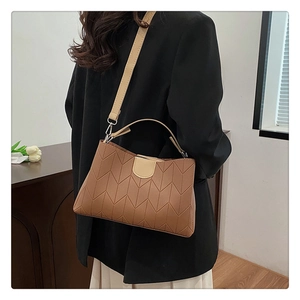 Detailed view of quilted faux leather crossbody bag with V-shaped stitching pattern