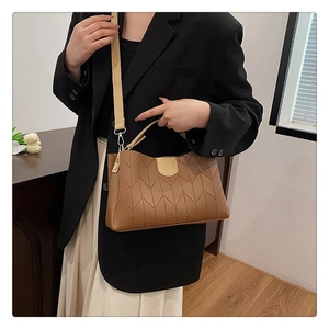 Detail view of brown quilted tote bag with adjustable strap worn by a female model