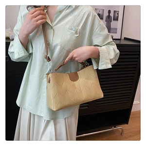 Detail of beige crossbody bag with herringbone stitching and brown buckle trim