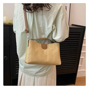 Detail of chevron quilted cream handbag with contrasting brown straps worn by model
