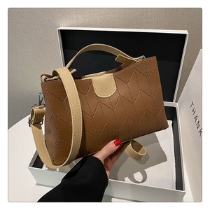 Detail showing vintage V-stitched PU leather crossbody bag in beige and brown colors