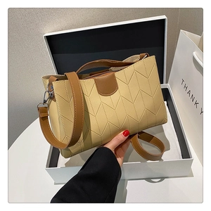 Close-up of a beige crossbody bag with V-shaped stitching in a premium gift box set