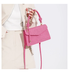 Close-up of pink woven texture handbag with knotted handle and elegant gold hardware