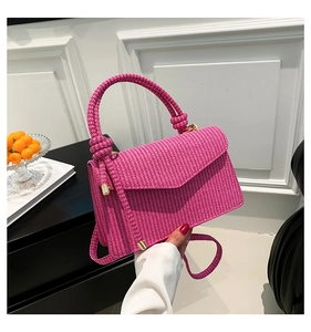Detail of rose pink woven handbag with geometric texture and gold metal hardware