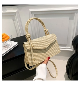 Detail of woven texture handbag with knotted handle and beige V-shaped flap design