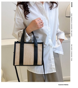Dettaglio borsa tote in paglia intrecciata con finiture in pelle nera indossata da modella
