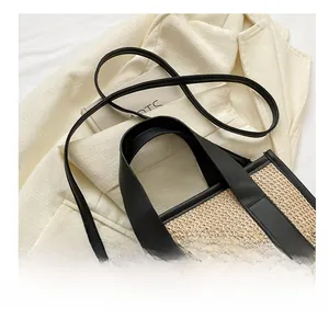 Dettaglio della borsa tote in paglia intrecciata con spalline in pelle nera a contrasto