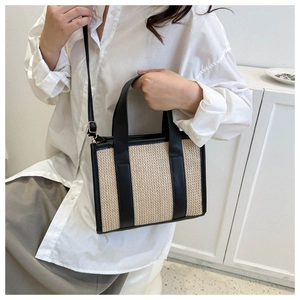 Dettaglio della borsa in paglia beige con finiture e manici in pelle nera