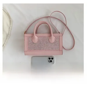 Pink studded mini square handbag next to a smartphone for clear size comparison