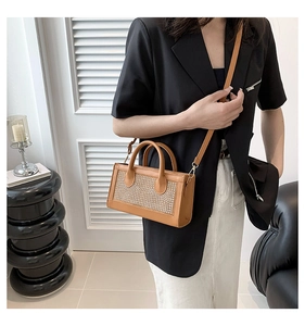 Sac à main chic en cuir marron avec panneau en strass brillant tenu par un modèle