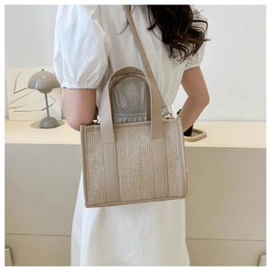 Borsa tote intrecciata beige con finiture in pelle indossata a tracolla moda