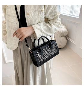 Détail d'un sac à main carré noir chic avec des strass étincelants et deux poignées