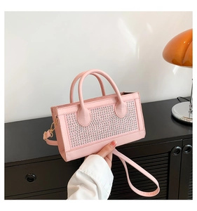 Sac à bandoulière rose avec rivets argentés et doubles poignées dans un décor moderne
