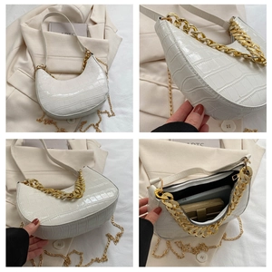 Detalle del bolso hobo blanco con grabado de cocodrilo, cadena dorada y cremallera