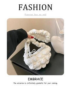 Detail of white quilted puffy handbag with textured grid fabric and knotted handle