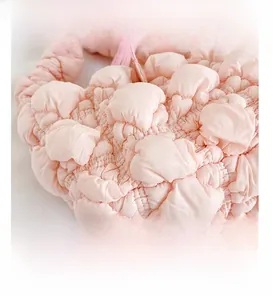Detail presentation of light pink bubble bag featuring soft textured pleated fabric