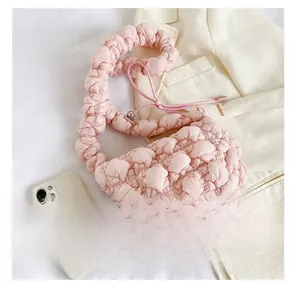 Pink popcorn fabric shoulder bag showing pleated texture and size comparison to phone