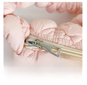 Detail of smooth silver zipper and quilted puffy texture on a light pink cloud bag