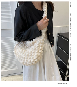 Detail of white popcorn textured fabric on a stylish crescent-shaped shoulder bag