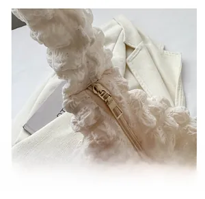Close-up of smooth gold zipper and white bubble textured fabric on pleated shoulder bag