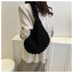 Detail of black popcorn texture shoulder bag showing 3D bubble fabric and soft drape