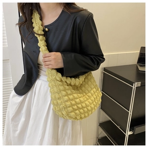Detail of yellow shoulder tote bag with 3D popcorn texture shown on a model