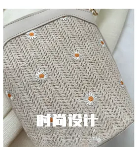 Gros plan sur le tissage à chevrons et la broderie de marguerites du sac tressé