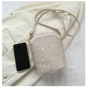 Détail du sac bandoulière en paille avec broderie marguerite et lanière en cuir beige