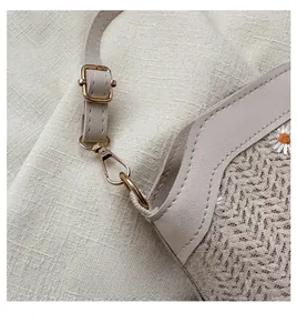 Détail macro du crochet en métal, de la bandoulière et de la broderie de marguerites