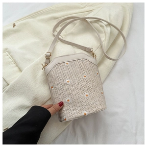Détail du sac seau en paille avec broderie florale et bandoulière en cuir réglable