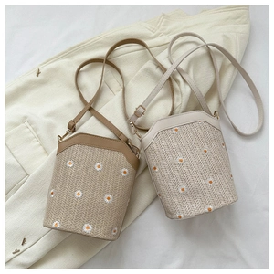Détail de sacs seaux en paille avec broderie marguerite et bandoulières en cuir