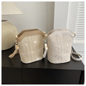 Detail of woven straw bucket bags with daisy embroidery and adjustable leather straps