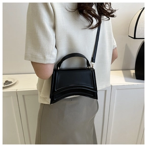 Détail d'un sac à main noir en cuir sablier avec bandoulière réglable et amovible