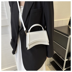 Détail du sac à main sablier blanc avec base incurvée et garniture en métal doré