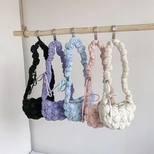 Quilted bubble shoulder bags with ruffle straps in multiple colors hanging on a rod
