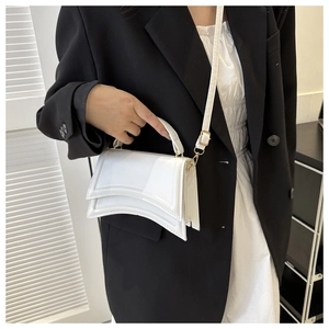 Détail du sac à main sablier blanc brillant avec base incurvée et boucle dorée sur modèle