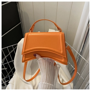 Détail d'un sac à main géométrique orange vif avec des couches de cuir incurvées élégantes