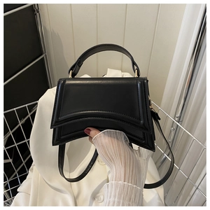 Détail du sac à main sablier noir avec base incurvée et garniture dorée à la main